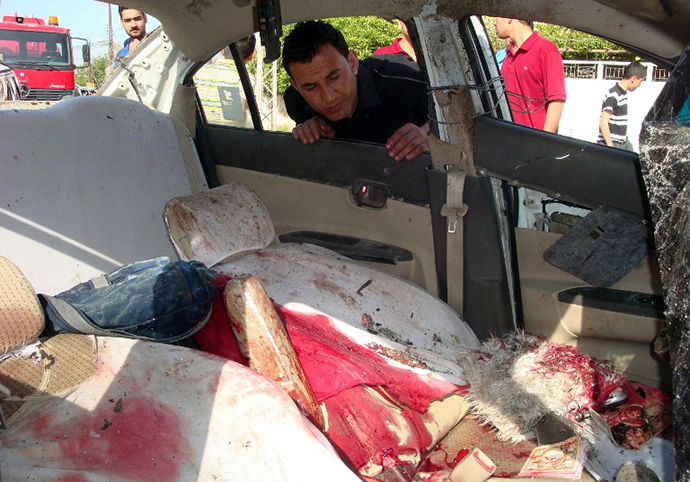 A man looks inside the blood stained vehicle following an explosion in the northern Iraqi city of Kirkuk on April 15, 2013. (AFP Photo / Marwan Ibrahim)