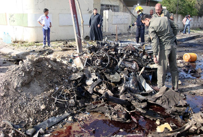 A man looks at the remains of a car bomb in the northern Iraqi city of Kirkuk on April 15, 2013. (AFP Photo / Marwan Ibrahim)