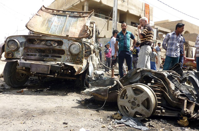 Iraqis look at the remains of vehicles damaged following an explosion in the al-Obaidi neighborhood, east of Baghdad on April 15, 2013. (AFP Photo / Ali Al-Saadi)