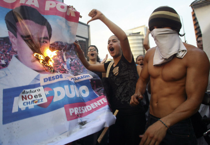 Supporters of Venezuelan opposition presidential candidate Henrique Capriles burn a banner of new proclaimed President Nicolas Maduro in Caracas on April 15, 2013 (AFP Photo / Geraldo Caso) 