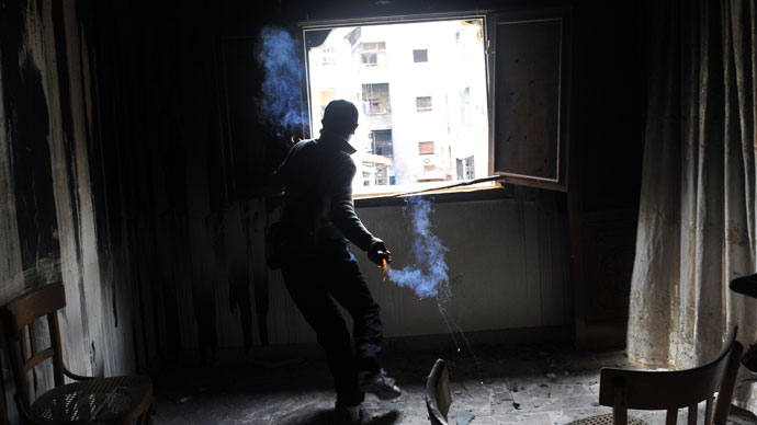 A rebel fighter throws a homemade grenade towards Syrian government forces through a window at a flat in the Salaheddine neighbourhood of Aleppo on February 16, 2013.(AFP Photo / Bulent Kilic)