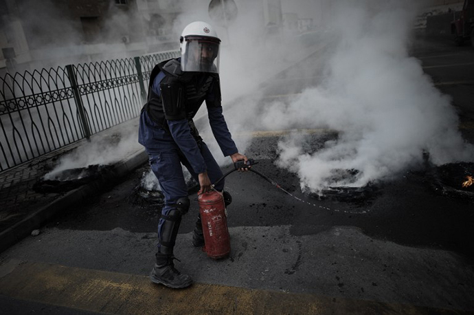 A Bahraini Policeman extinguishes tyres burning during clashes with riot police following a protest against the arrival of Bahrain Formula One Grand Prix on April 18, 2013 in the village of Diraz, west of Manama. (AFP Photo / Mohammed Al-Shaikh)