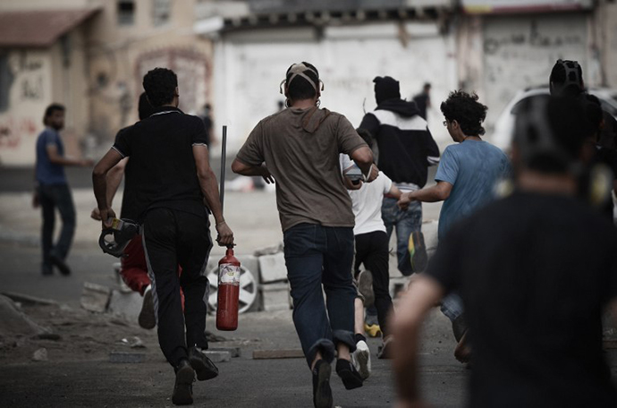  A Bahraini protester runs away carrying a pressurized fire extinguisher that is used to shot iron arrows towards riot police during clashes following a protest against the arrival of Bahrain Formula One Grand Prix on April 18, 2013 in the village of Diraz, west of Manama. (AFP Photo / Mohammed Al-Shaikh)