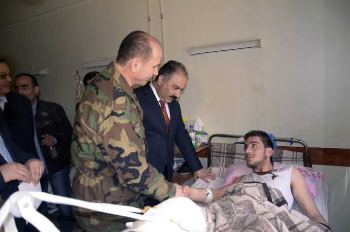 Syrian government officials and military personnel visit a victim of chemical weapons at a hospital in Aleppo, March 21, 2013. (Reuters/George Ourfalian)