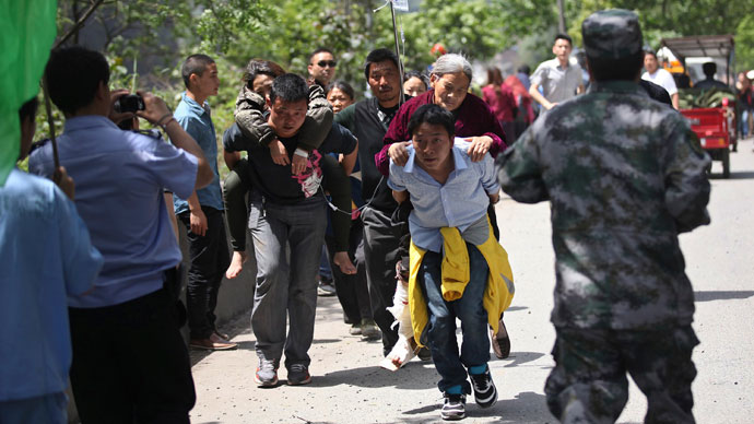 Men carry injured people to an ambulance at Longmen Village, Lushan county, Ya'an, Sichuan province, April 20, 2013.(Reuters / Stringer)