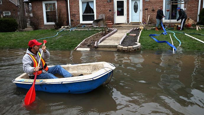 Octavio Castillo paddles a boat down a flooded street to reach the home of his cousin on April 19, 2013 in Des Plaines, Illinois.(AFP Photo / Scott Olson)