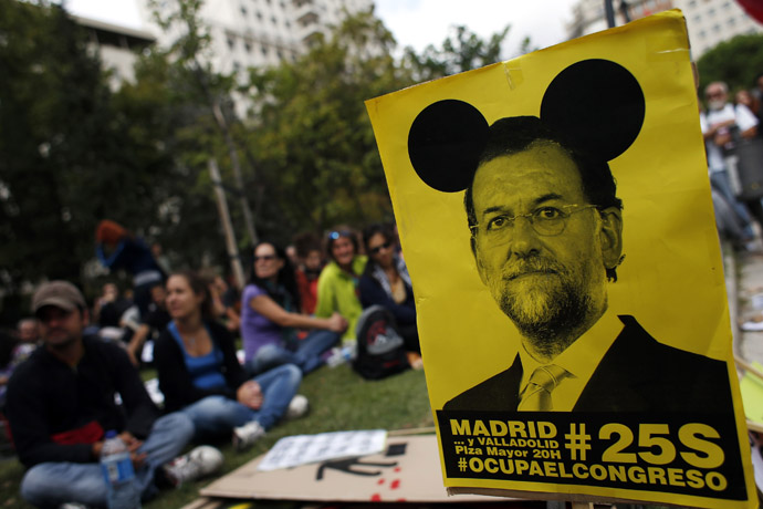 Demonstrators sit next to a sign with an image of Spanish Prime Minister Mariano Rajoy as they wait for the start of an assembly before an anti-austerity demonstration in Madrid September 25, 2012. (Reuters)