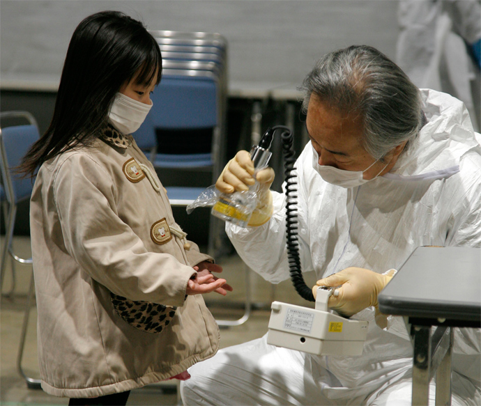 A little girl holds out her hands for a radiation scan at a screening center in Koriyama in Fukushima prefecture (AFP Photo)