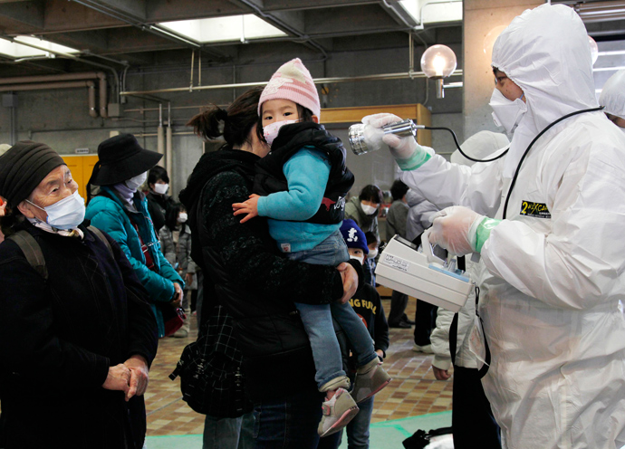 An official in a full radiation protection suit scans an evacuated mother and child with a geiger counter to check radiation levels in Koriyama city in Fukushima prefecture, about 60km west from the crisis-hit Tokyo Electric Power Co (TEPCO) Fukushima Nuclear plant (AFP Photo / Ken Shimizu)