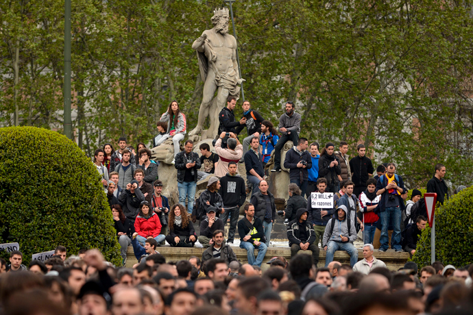 People gather on the Neptune fountain in front of fences blocking the street leading to the Spain's parliament (Las Cortes) during an anti-government demonstration in Madrid on April 25, 2013 (AFP Photo / Pedro Armestre)