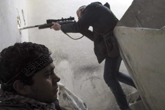 A member of the Free Syrian Army points his weapon through a hole in a wall as he takes up a defence position near Aleppo International Airport February 15, 2013. (Reuters/Saad Abobrahim)