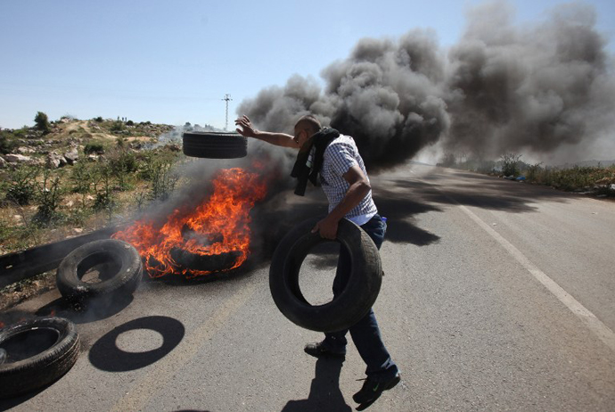 A Palestinian demonstrator burns tyres during during clashes with Israeli soldiers following a march against construction on their land by members of the nearby Jewish settlement of Ofra on April 26, 2013. (AFP Photo / Abbas Momani)