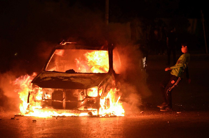 An Egyptian child kicks a burning police van after unknown attackers torched it during clashes outside the Egyptian presidential palace on April 26, 2013 in Cairo, Egypt. (AFP Photo / Mohamed El-Shahed)