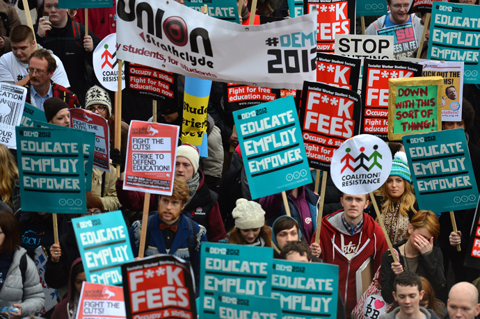 Demonstrators hold placards as they gather before the start of a student rally in central London against sharp rises in university tuition fees, funding cuts and high youth unemployment (AFP Photo / Ben Stansall)