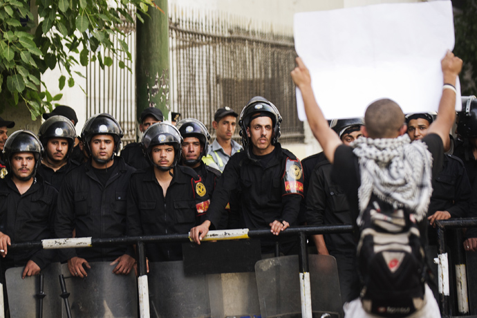 Police look on as students from Cairo University march towards the Egyptian Prime Minister's office on April 28, 2013 in Cairo (AFP Photo / Gianluigi Guercia) 