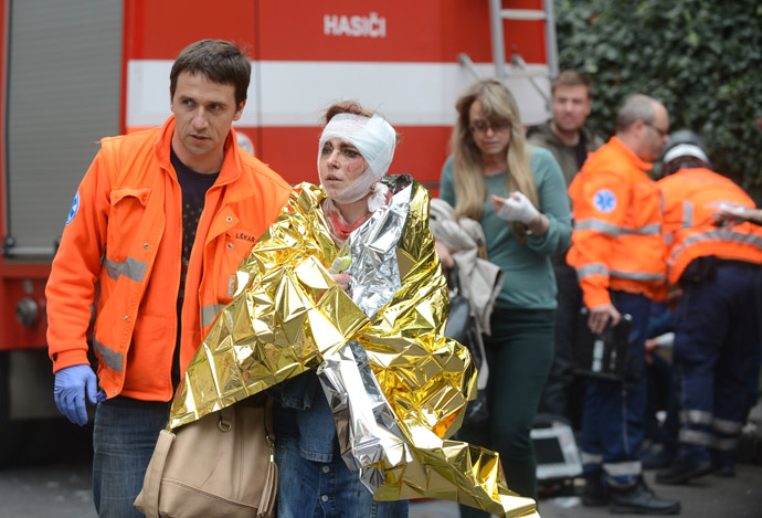 Rescue workers help a woman who was injured in a blast next to the building where an explosion happened on April 29, 2013 in Prague, Czech Republic. (AFP Photo/Michal Cizek)