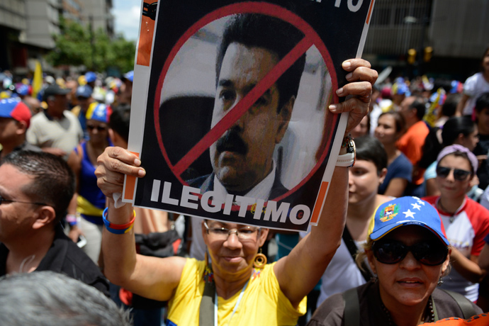 An opponent of the Venezuelan government shows a poster with a portrait of Venezuelan President Nicolas Maduro reading "Illegitimate" during a May Day demonstration in Caracas on May 1, 2013 (AFP Photo / Leo Ramirez)