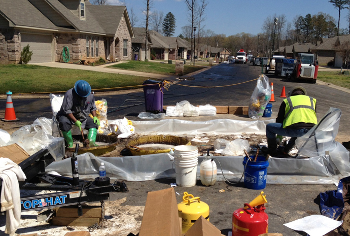 Workers scrub crude oil from their boots in the Northwoods subdivision where an ExxonMobil pipeline ruptured in Mayflower, Arkansas, April 1, 2013 (Reuters / Suzi Parker)