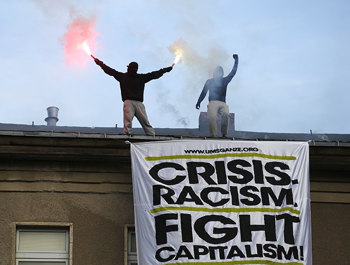 Demonstrators burn flares on the roof of a building above a huge placard during May Day protests in Berlin, May 1, 2013. (Reuters /Fabrizio Bensch) 