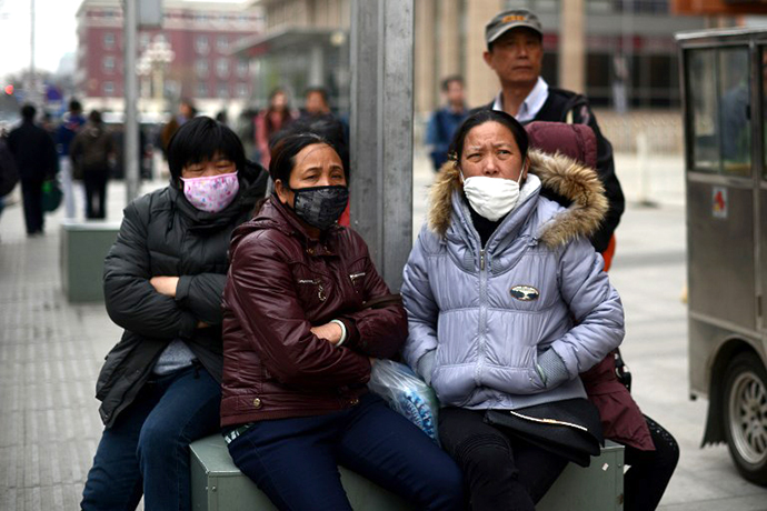 A group of Chinese women wear face masks as they sit on a street side in Beijing on April 19, 2013. (AFP Photo / Wang Zhao)