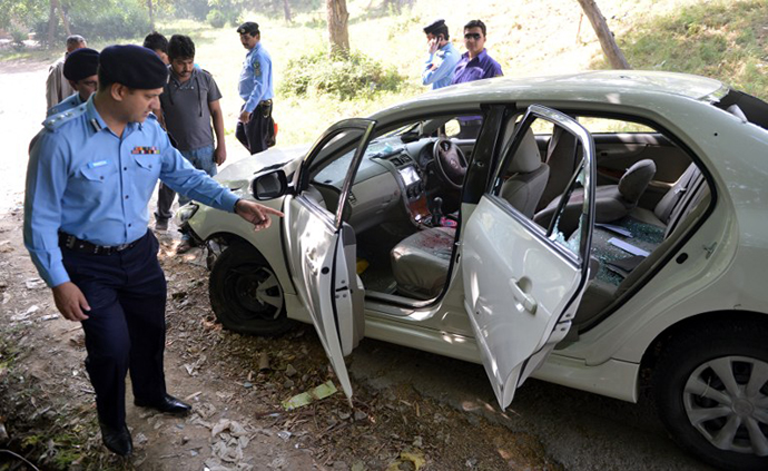 Pakistani police officials examine the bullet-riddled car of slain government prosecutor Chaudhry Zulfiqar after an attack by gunmen in Islamabad on May 3, 2013. (AFP Photo / Aamir Qureshi)