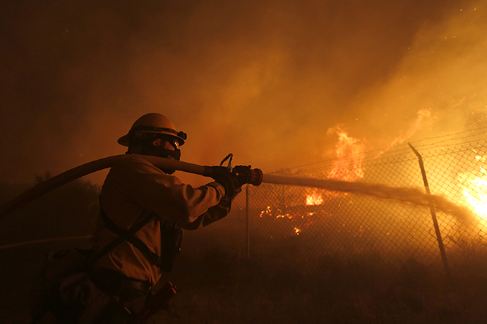 A firefighter battles to protect a CalTrans Maintenance Station and Fuel Depot from the Springs Fire near Pacific Coast Highway and the Los Angeles County Line at Malibu, California, May 2, 2013. (Reuters / Patrick Fallon)