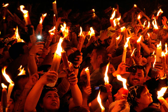 Christian Orthodox worshippers hold up candles lit from the 'Holy Fire' as thousands gather in the Church of the Holy Sepulchre in Jerusalem's old city on May 4, 2013.(AFP Photo / Gali Tibbon)