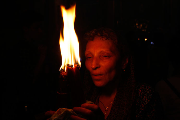 A Christian Orthodox worshipper holds up candles lit from the 'Holy Fire' as thousands gather in the Church of the Holy Sepulchre in Jerusalem's old city on May 4, 2013.(AFP Photo / Gali Tibbon)