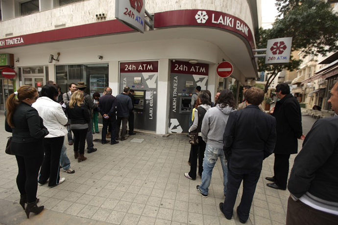 Cypriots and foreigners wait in line to withdraw money from an ATM of a Laiki (Popular) Bank branch in the old city of the capital, Nicosia, on March 21, 2013. (AFP Photo / Patrick Baz)