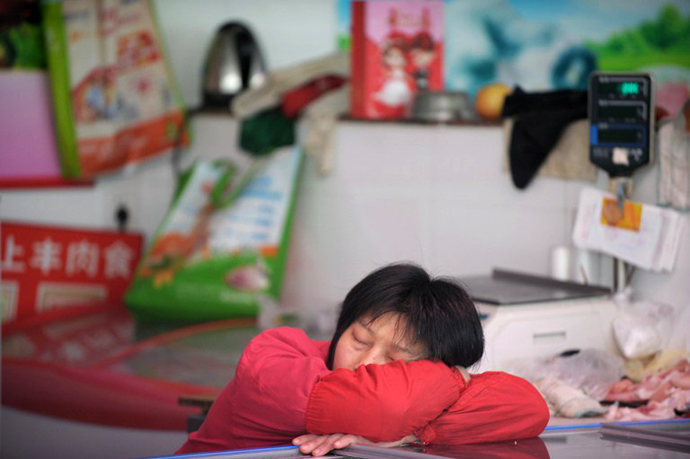 A pork seller takes a nap in a wet market in Shanghai on April 15, 2013. (AFP Photo / Peter Parks)