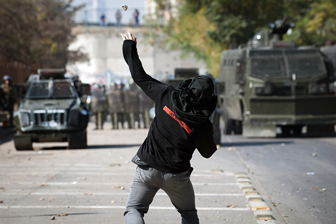A student throews stines to riot police during a protest to demand Chilean President Sebastian Pinera's government to improve the public education quality, in Santiago, on May 8, 2013. (AFP Photo / Claudio Santana)