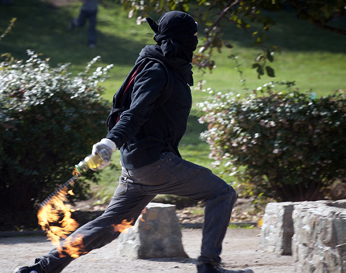 A student throws a molotov cocktail to riot policemen during a protest to demand Chilean President Sebastian Pinera's government to improve the public education quality, in Santiago, on May 8, 2013. (AFP Photo / Claudio Santana)