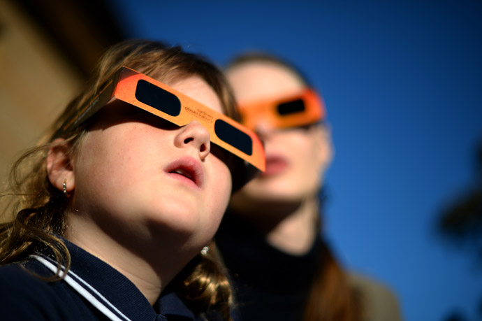A child (L) watches a partial solar eclipse with a woman at the Sydney Observatory on May 10, 2013. (AFP Photo/Saeed Khan)