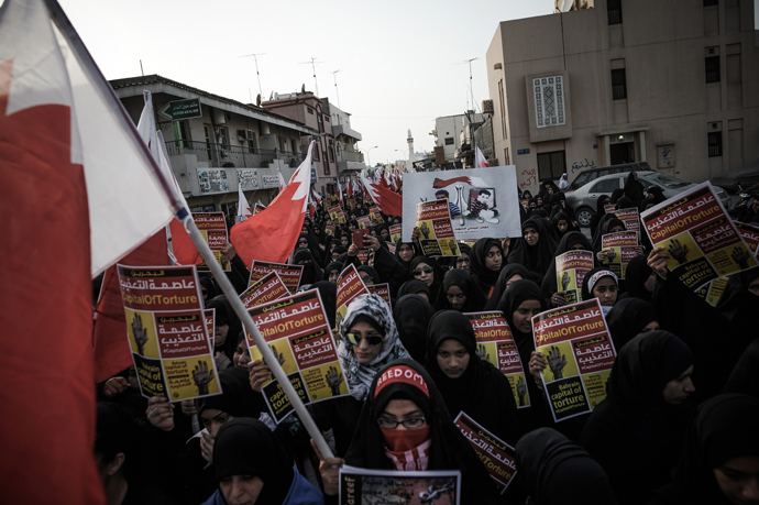 Bahraini women hold up placards and wave the national flag during an anti-government protests in the village of Jidhafs, west of Manama, on May 10, 2013 (AFP Photo / Mohammed Al-Shaikh)