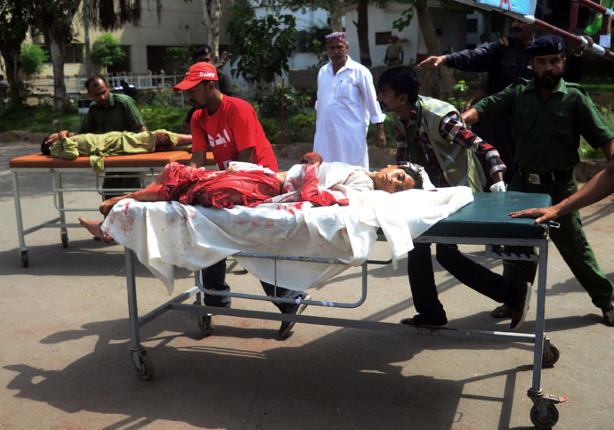 Pakistani volunteers carry injured blast victims to a hospital following a bomb explosion in Karachi on May 11, 2013. (AFP Photo/Rizwan Tabasssum)