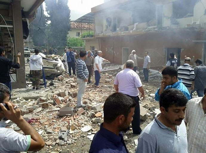 People stand on the site where car bombs exploded on May 11, 2013 near the town hall in Reyhanli, just a few kilometres from the main border crossing into Syria. (AFP Photo/IHLAS NEWS AGENCY)