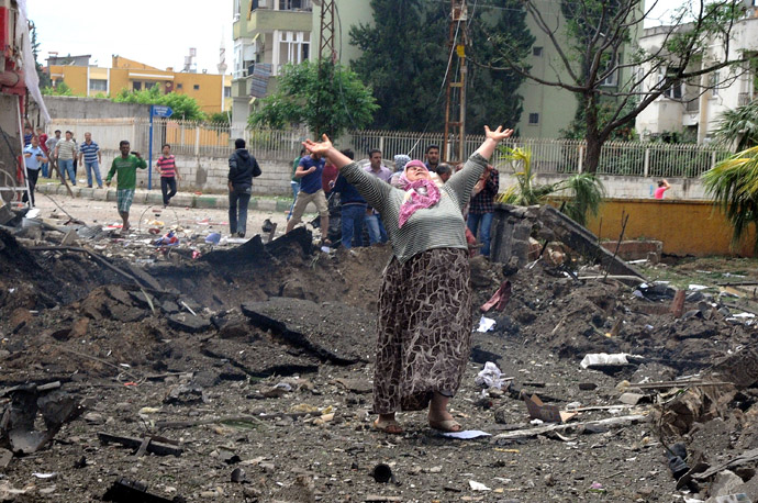 A woman raises her arms and shouts as she stands on the site where car bombs exploded on May 11, 2013 near the town hall in Reyhanli, just a few kilometres from the main border crossing into Syria (AFP Photo/IHLAS NEWS AGENCY)
