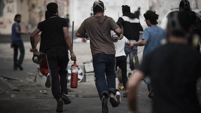 A Bahraini protester runs away carrying a pressurized fire extinguisher that is used to shot iron arrows towards riot police during clashes following a protest against the arrival of Bahrain Formula One Grand Prix on April 18, 2013.(AFP Photo / Mohammed Al-Shaikh)