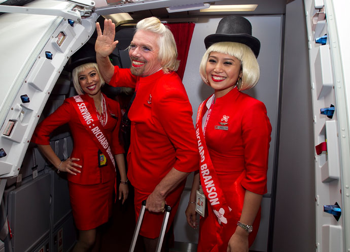 British billionaire Richard Branson (C) waves before boarding an AirAsia flight bound for Kualu Lumpur to work as a flight attendant at Perth Airport on May 12, 2013.(AFP Photo / Tony Ashby)