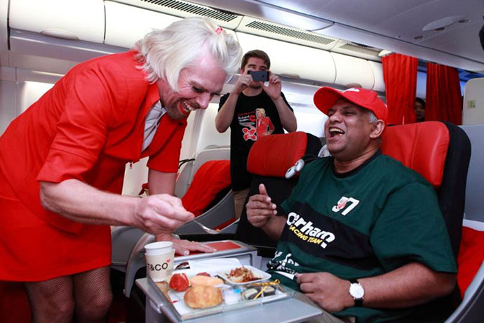  Tony Fernandes (R) being served by British billionaire Richard Branson (L), who is dressed as a female flight attendant, in the air while flying from the Australian city of Perth to the Malaysian city of Kuala Lumpur. Branson honoured a losing bet by serving as a stewardess with Fernandes over whose Formula One racing team would finish ahead of each other at the Abu Dhabi race during their debut 2010 season.(AFP Photo / Aair Asia) 