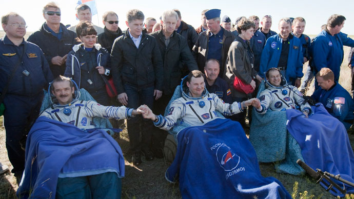 US astronaut Tom Marshburn (R), Canadian spaceman Chris Hadfield (L) and Russian cosmonaut Roman Romanenko (C) join their hands as they rest shortly after the landing aboard the Russian Soyuz space capsule some 150 km (90 miles) southeast of the town of Zhezkazgan in central Kazakhstan on May 14, 2013.(AFP Photo / Sergei Remezov)