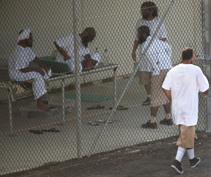 In this photo reviewed by US military officials, one detainee jogs by as others relax together in the exercise yard at Camp VI, part of the US Detention Center at Guantanamo Bay, Cuba (AFP Photo / Paul J. Richards)
