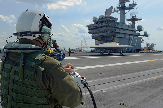 This May 10, 2013 US Navy handout image shows Dave Lorenz, a Northrop Grumman deck operator, driving an X-47B Unmanned Combat Air System (UCAS) demonstrator using an arm-mounted controller on the flight deck of the aircraft carrier USS George H.W. Bush (CVN 77) while docked in Norfolk, Virginia. (AFP/Handout/US Navy/MC2 Timothy Walte)