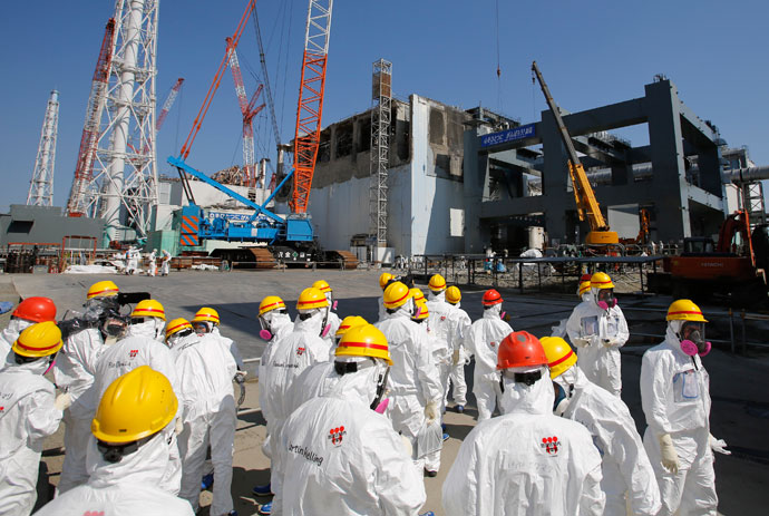 Members of the media wearing protective suits and masks are escorted by Tokyo Electric Power Co (TEPCO) employees as they visit near the No.4 reactor (C) and the construction of a foundation (R) for storage of melted fuel rods at TEPCO's tsunami-crippled Fukushima Dai-ichi nuclear power plant in the town of Okuma, Fukushima prefecture on March 6, 2013.(AFP Photo / Issei Kato)