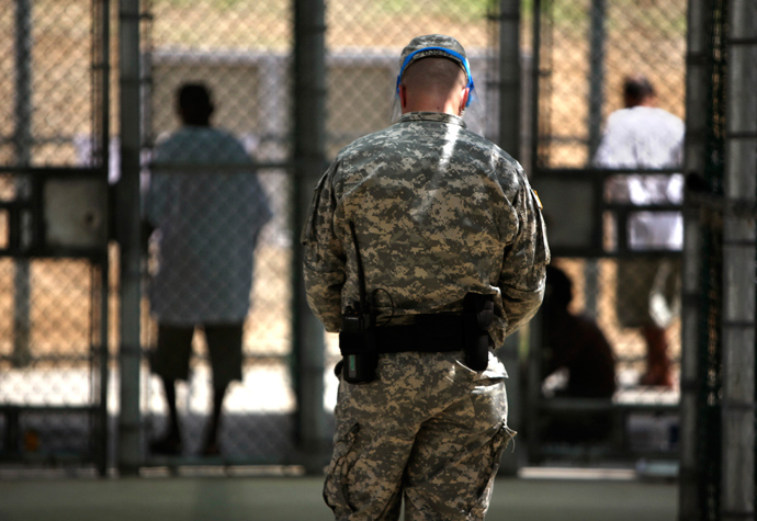 n this photo, reviewed by the U.S. military, and shot through glass, a guard watches over Guantanamo detainees inside the exercise yard at Camp 5 detention facility at Guantanamo Bay U.S. Naval Base, Cuba (Reuters / Brennan Linsley)