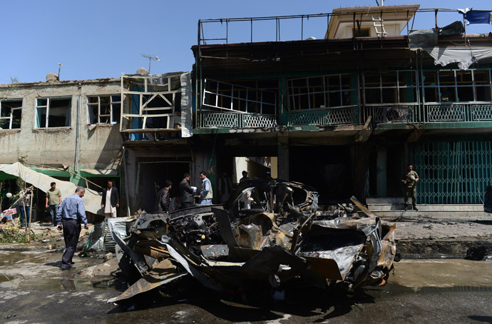 Afghan men walk around a destroyed US military vehicle at the site of a suicide attack in Kabul on May 16, 2013. (AFP Photo)