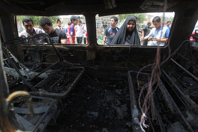 Iraqis inspect a burnt vehicle at the site of a car bombing at a market in Baghdad's impoverished district of Sadr City on May 16, 2013 as at least eight people were killed in blasts across the country. (AFP Photo)