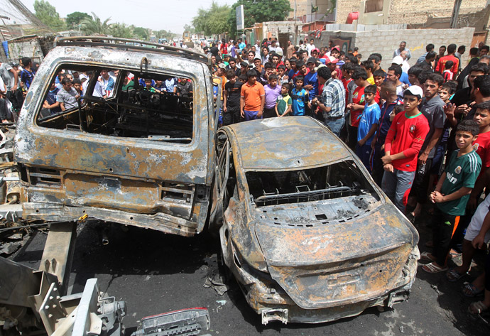 Iraqis gather around burnt vehicles at the site of a car bombing at a market in Baghdad's impoverished district of Sadr City on May 16, 2013 as at least eight people were killed in blasts across the country. (AFP Photo)