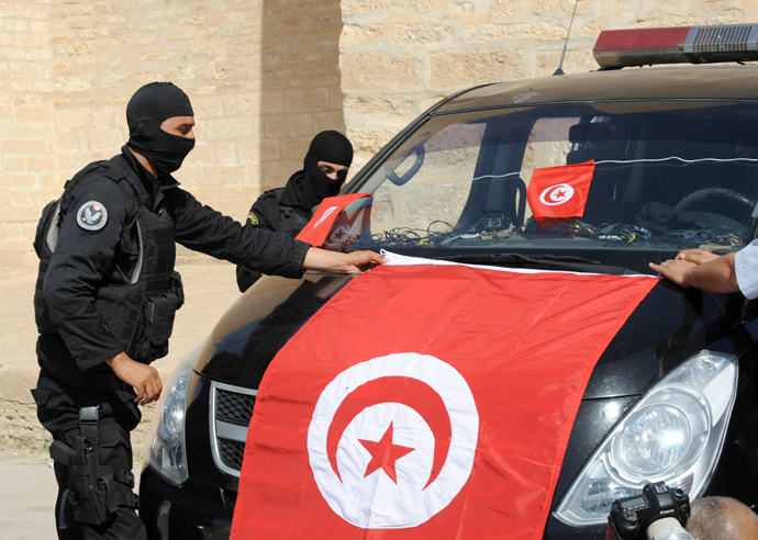 Tunisian Police Special Unit agents fix a national flag on their vehicle in front of the Okba Ibn Nafaa mosque in the central Tunisian city of Kairouan on May 19, 2013 (AFP Photo / Fethi Belaid)