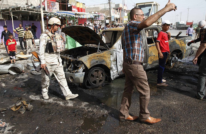 Iraqi citizens and soldiers inspect the scene of one of two car bombs that exploded in the main southern port city of Basra on May 20, 2013, that killed several and wounded dozens more, security and medical officials said, as a wave of attacks struck across the country. (AFP Photo / Ramzi Al-Shaban)